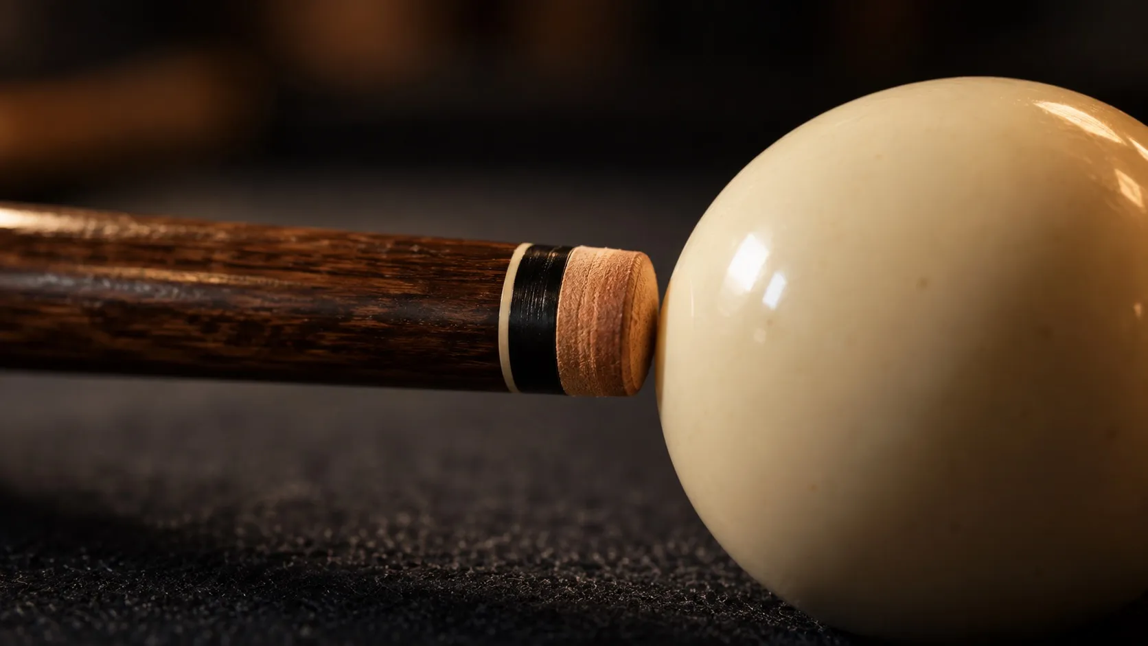 A cue tip positioned at the end of a cue beside a cue ball.
