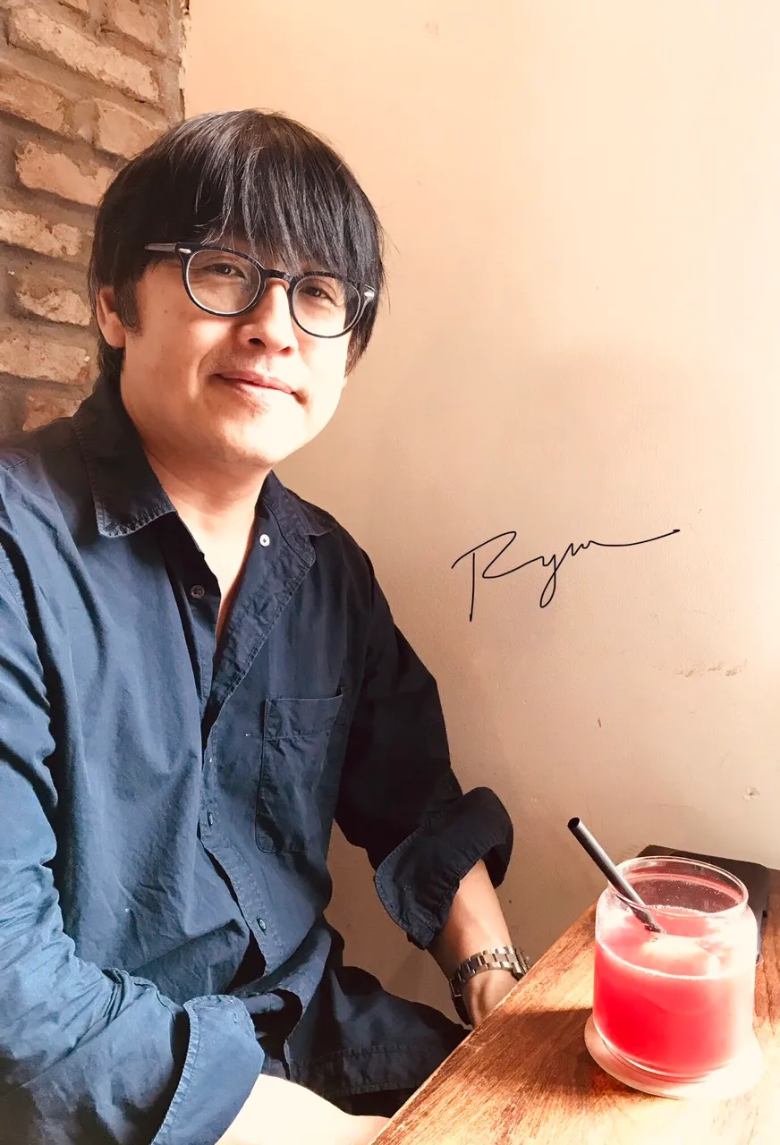 Ryu seated at a table indoors.