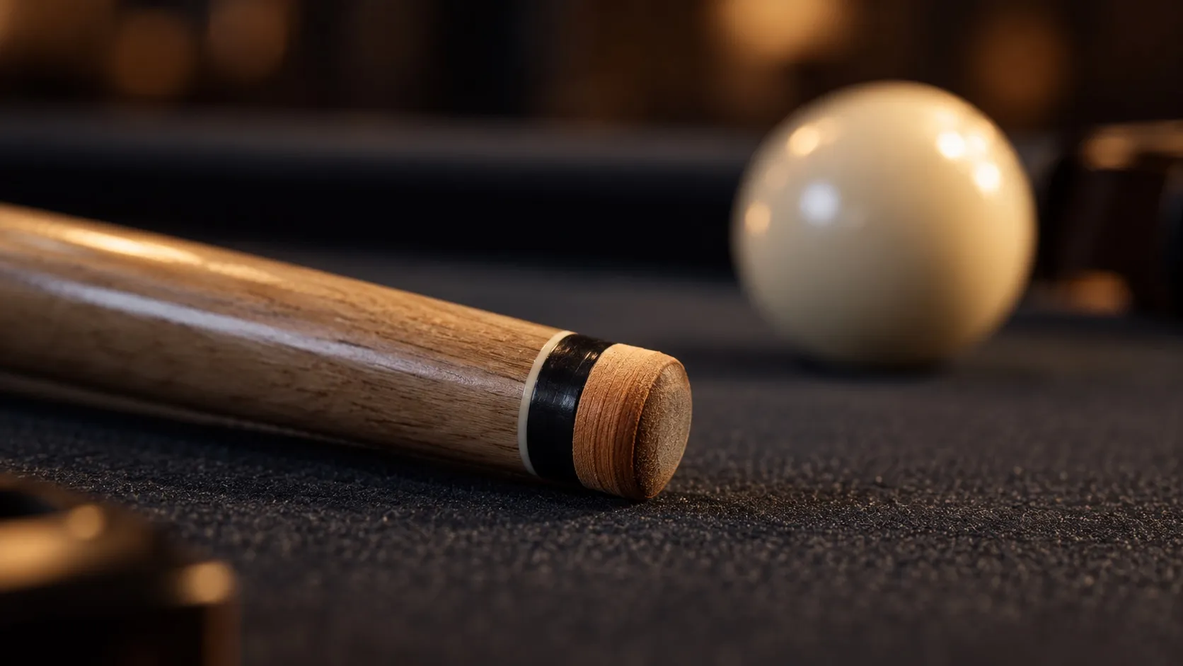 A cue tip installed at the end of a wooden billiard cue, with a cue ball behind it.